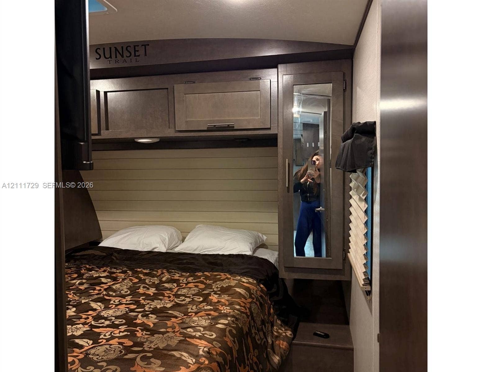Overhead storage cabinetry, horizontal plank wall accent, and full-length mirrored wardrobe closet