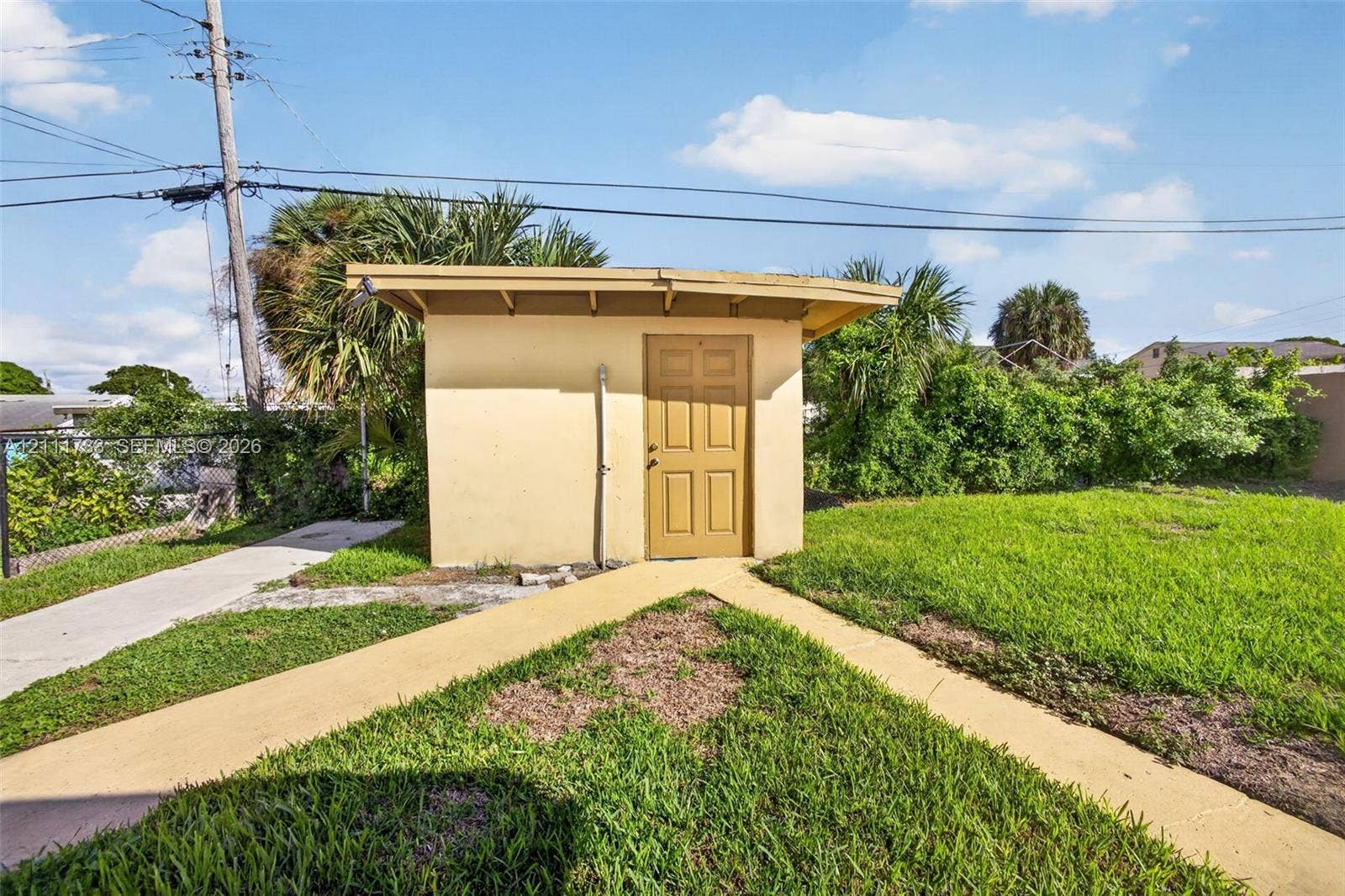 Exterior storage structure featuring a single-entry door and concrete walkway.