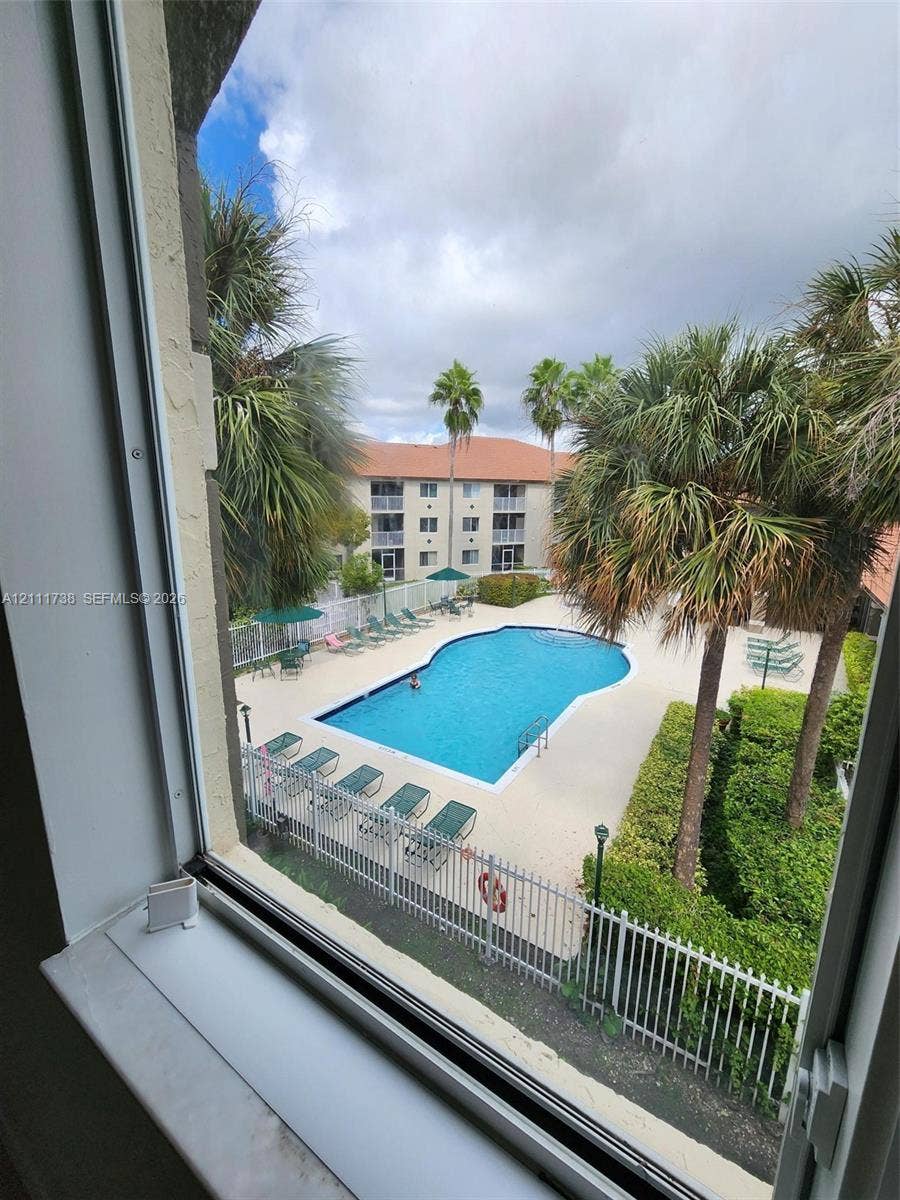 460 S Park Road, #308, Hollywood, Hollywood, FL 33021 Community swimming pool featuring a concrete deck, metal perimeter fencing, and surrounding palm trees