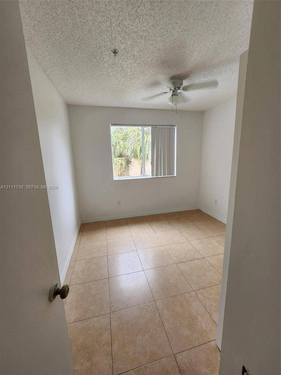 460 S Park Road, #308, Hollywood, Hollywood, FL 33021 Interior room featuring neutral ceramic tile flooring, a textured ceiling, a ceiling fan with light fixture, and a window with vertical blinds