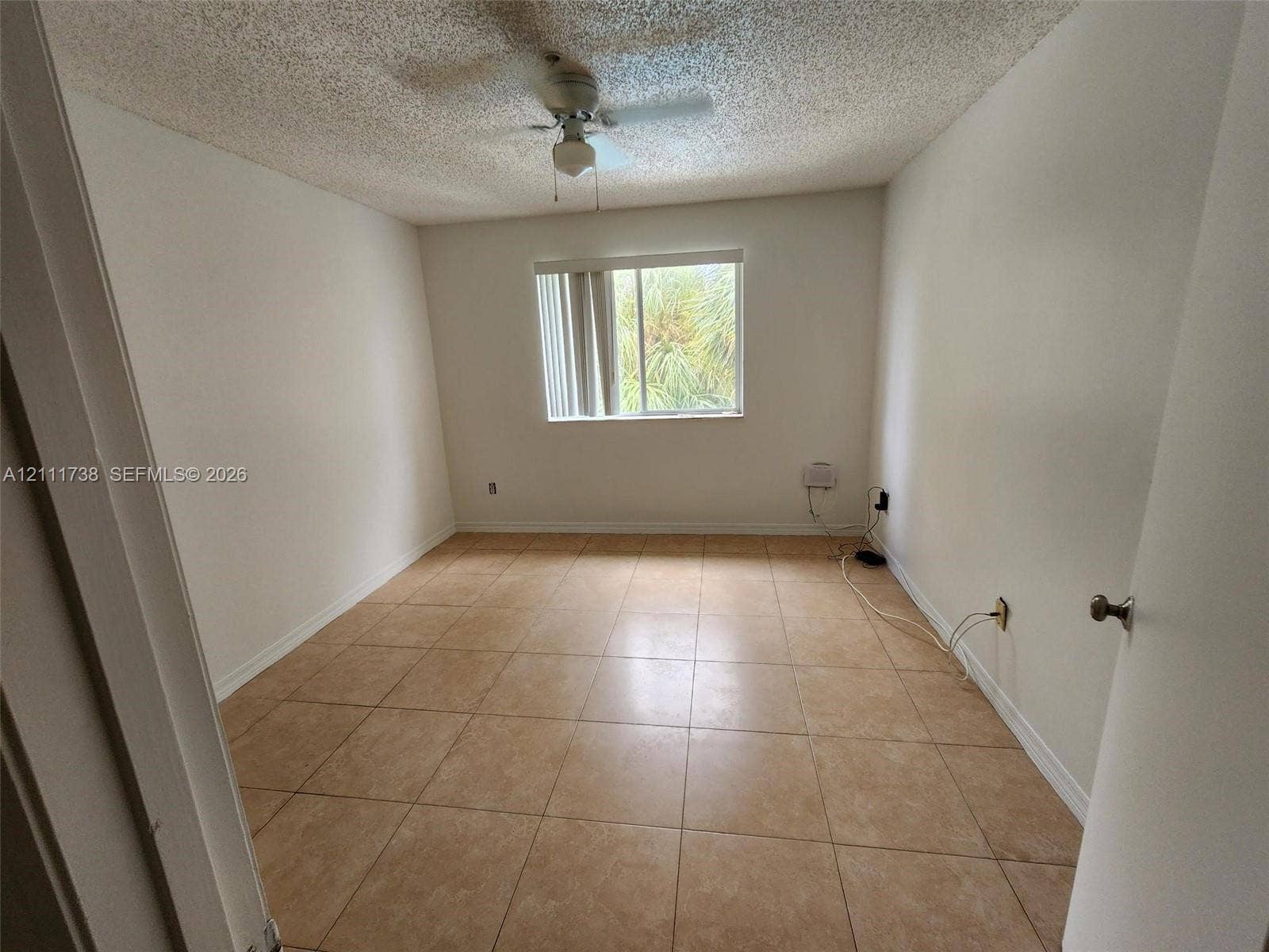 460 S Park Road, #308, Hollywood, Hollywood, FL 33021 Neutral-toned room featuring large-format square tile flooring, a textured ceiling, a central ceiling fan, and a single window with vertical blinds
