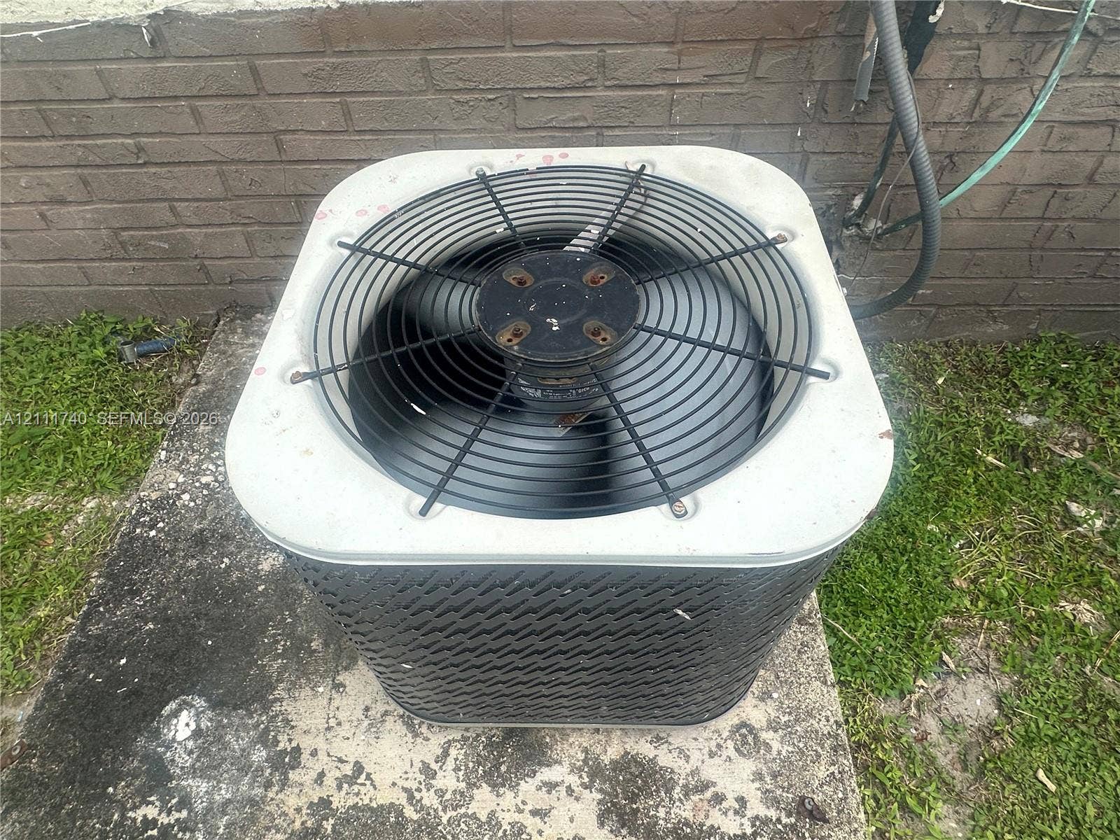 Exterior HVAC condensing unit situated on a concrete pad with brick masonry siding