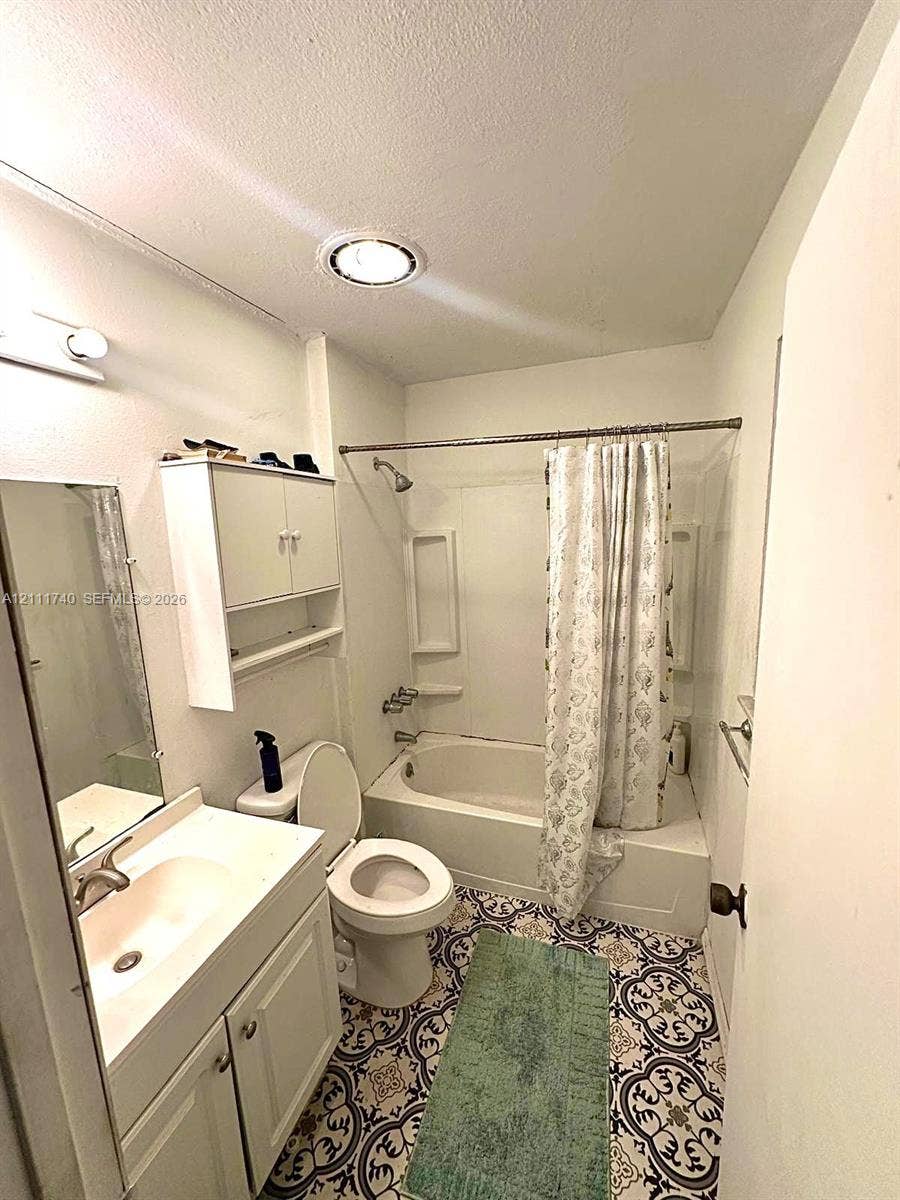 Bathroom featuring patterned tile flooring, vanity with integrated sink, wall-mounted cabinetry, and a tub-shower combination with recessed shelving