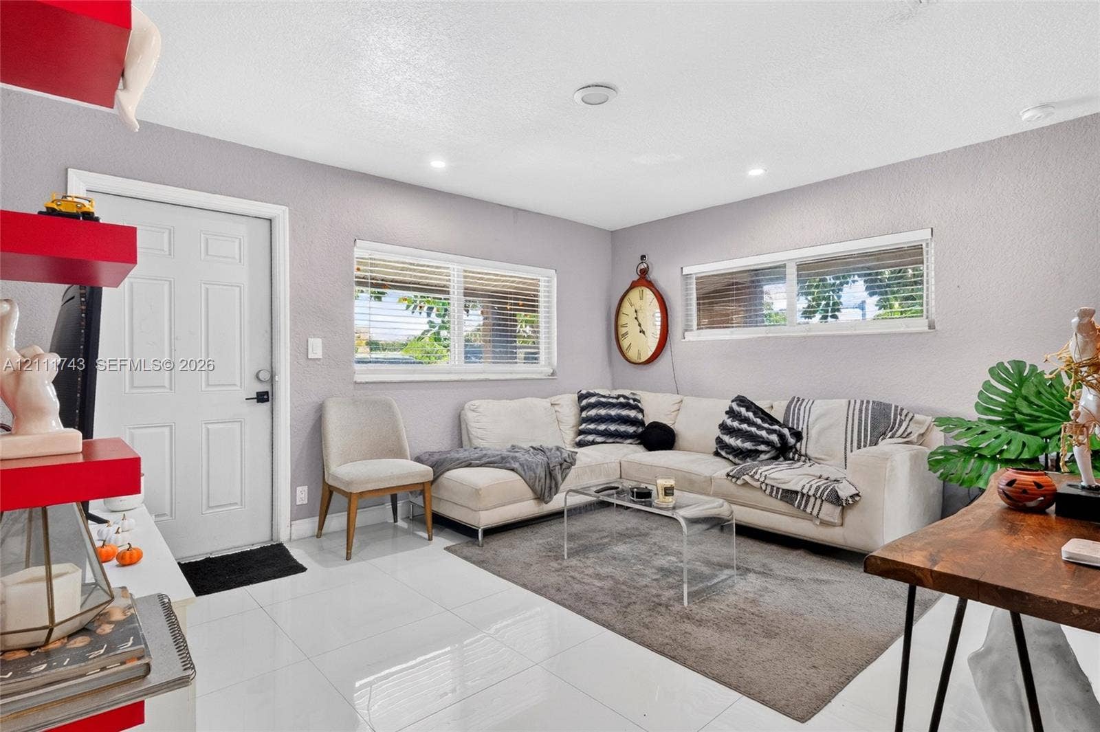 5524 N Andrews Avenue, Oakland Park, FL 33309 Interior space featuring large-format tile flooring, recessed ceiling lighting, dual windows with horizontal blinds, and a solid-core entry door