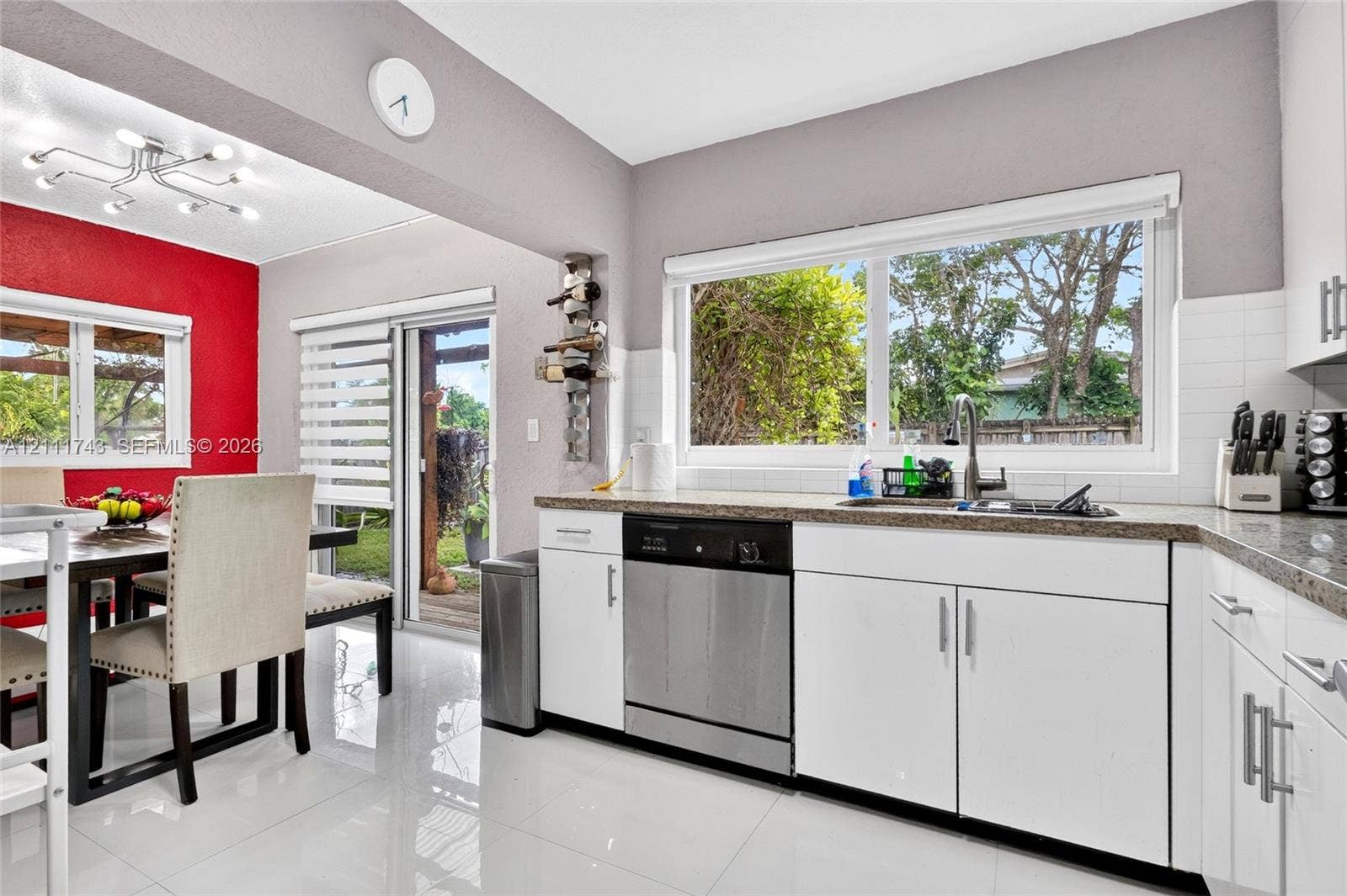 5524 N Andrews Avenue, Oakland Park, FL 33309 Kitchen featuring white cabinetry, stone-finish countertops, large-format tile flooring, a stainless steel dishwasher, and a multi-arm modern ceiling light fixture