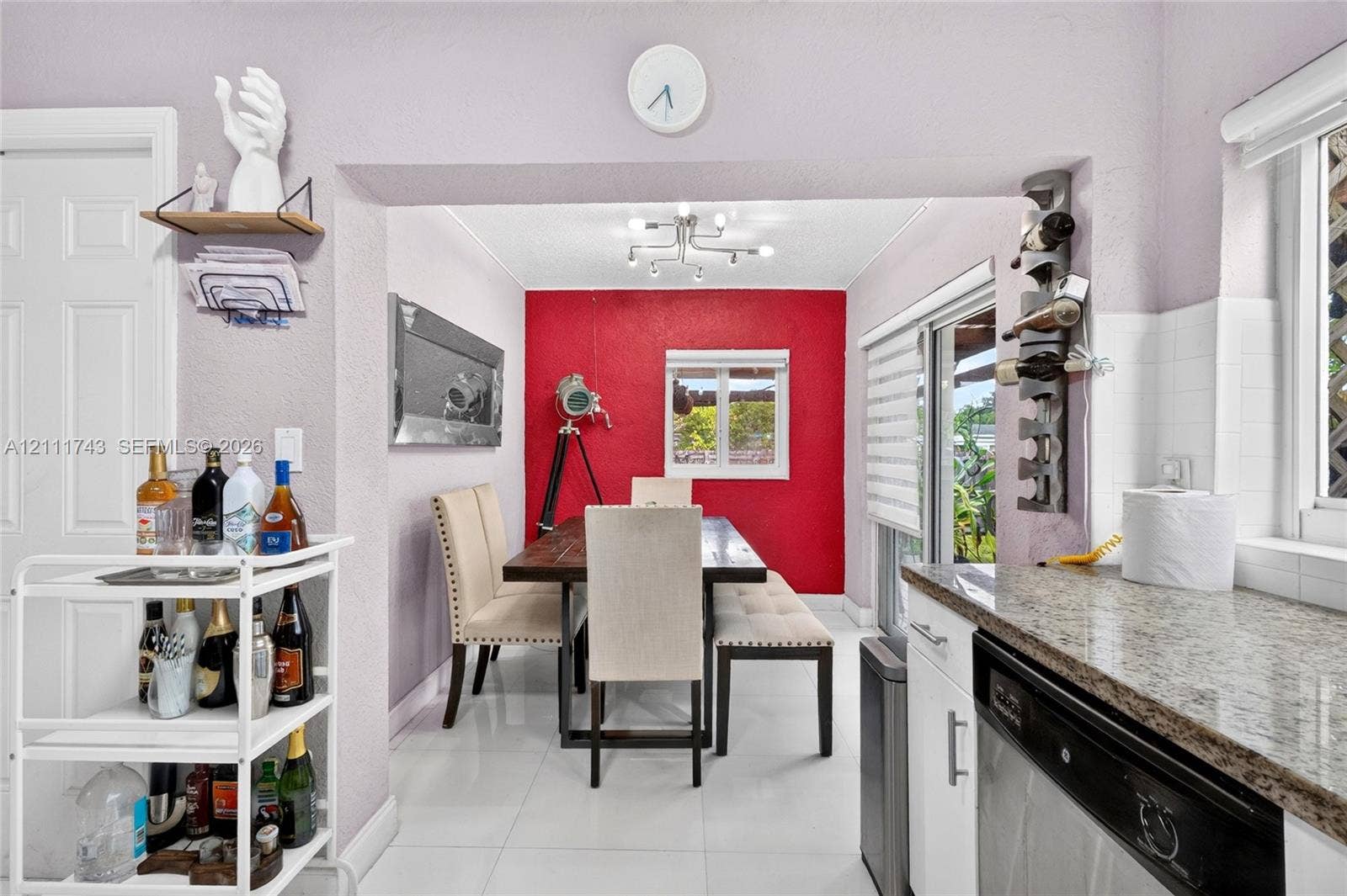 5524 N Andrews Avenue, Oakland Park, FL 33309 Dining area featuring stone-surfaced kitchen counters, white shaker-style cabinetry, a multi-arm modern light fixture, and sliding glass doors