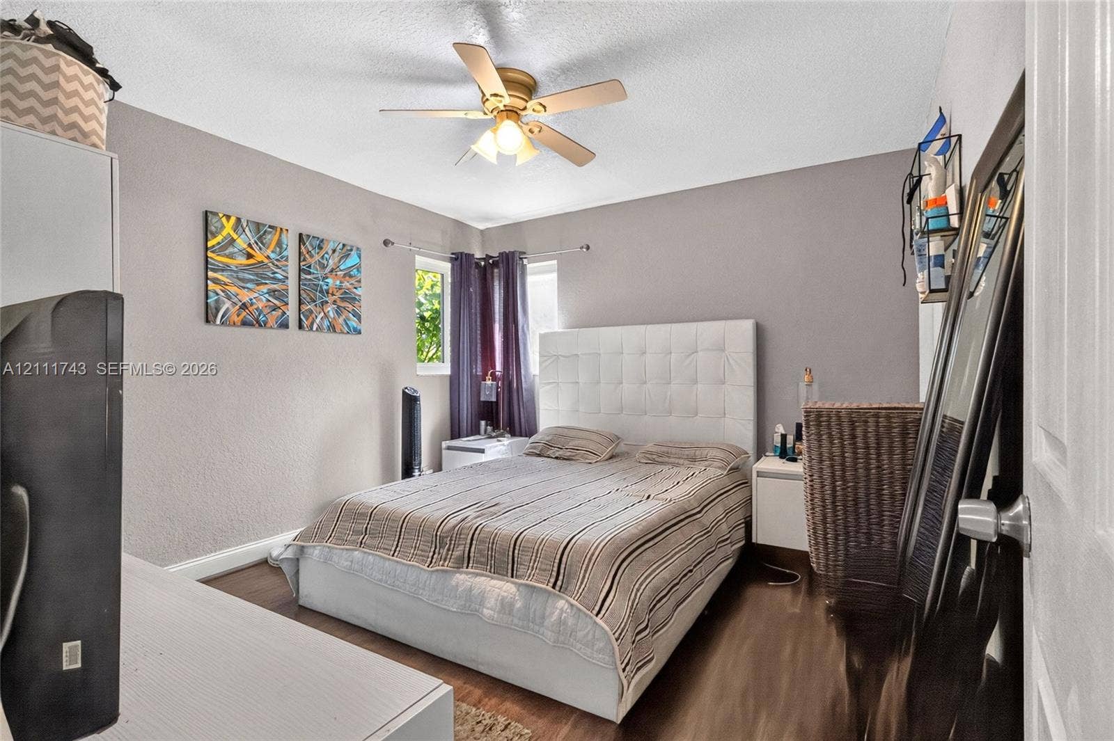 5524 N Andrews Avenue, Oakland Park, FL 33309 Neutral-toned interior featuring wood-finish flooring, a multi-blade ceiling fan, and corner windows