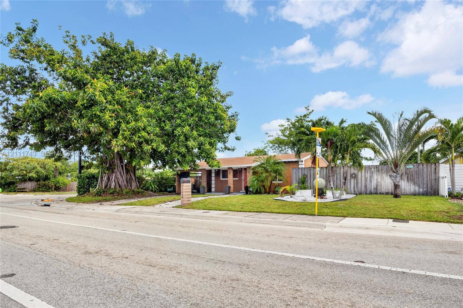 5524 N Andrews Avenue, Oakland Park, FL 33309 Single-story residence featuring a low-pitch roof, masonry exterior, established trees, and perimeter wood fencing