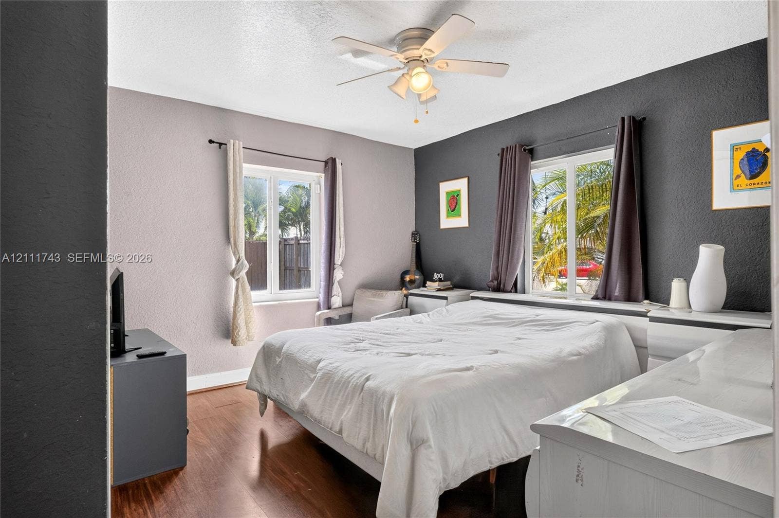 5524 N Andrews Avenue, Oakland Park, FL 33309 Room featuring wood-finish flooring, dual-tone painted walls, two multi-pane windows, and a central ceiling fan with an integrated light fixture
