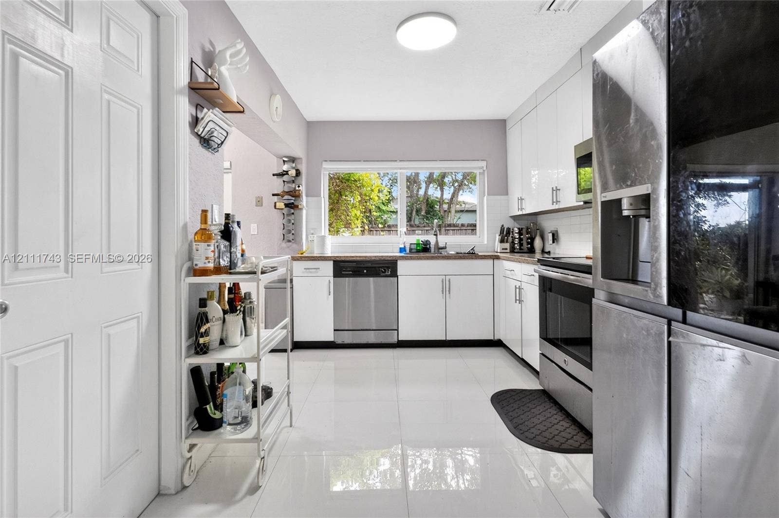 5524 N Andrews Avenue, Oakland Park, FL 33309 Kitchen featuring white cabinetry, stainless steel appliances, polished tile flooring, and a window above the sink