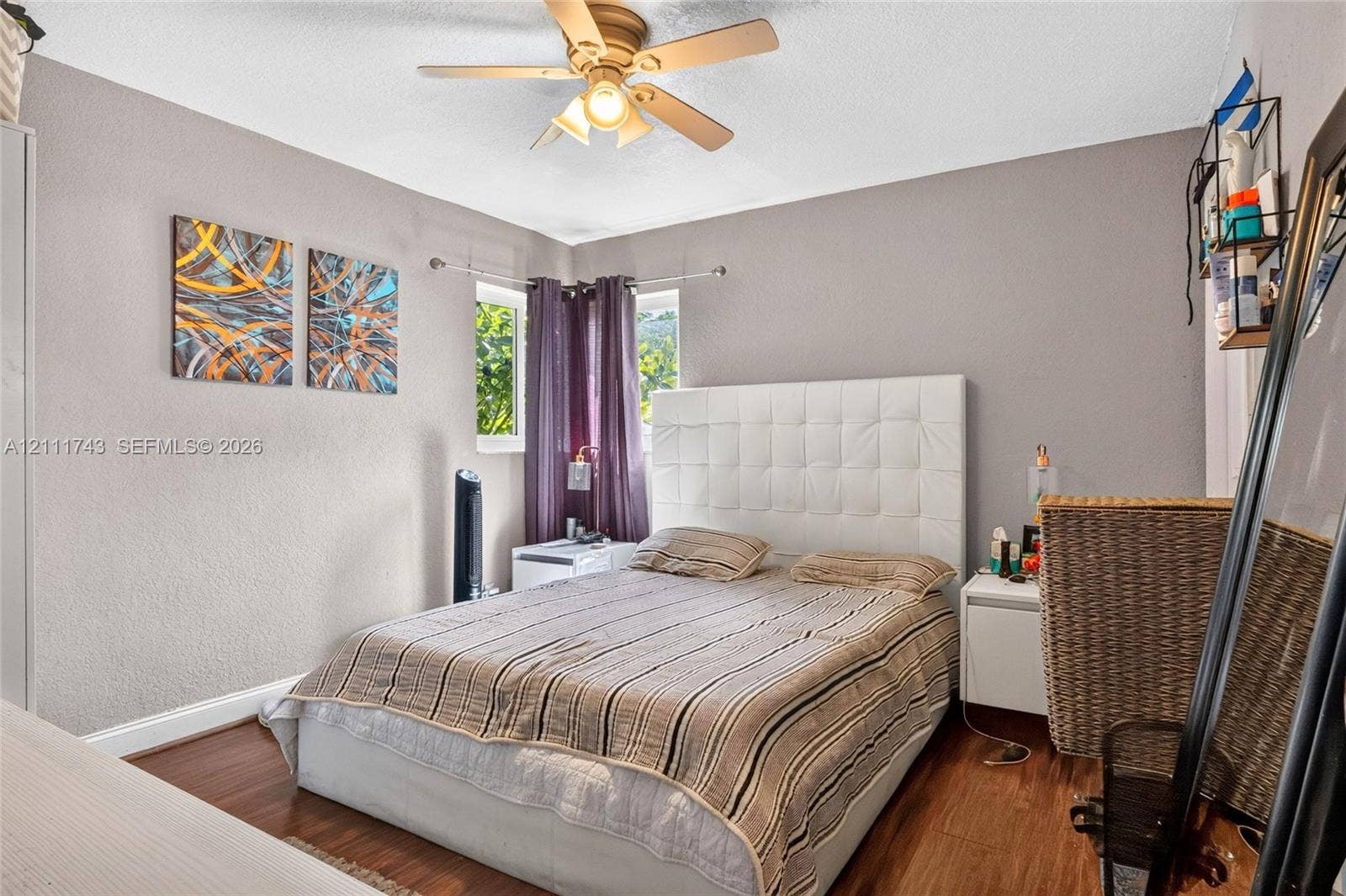 5524 N Andrews Avenue, Oakland Park, FL 33309 Bedroom featuring wood-finish flooring, a ceiling fan with integrated lighting, dual corner windows, and textured wall finish