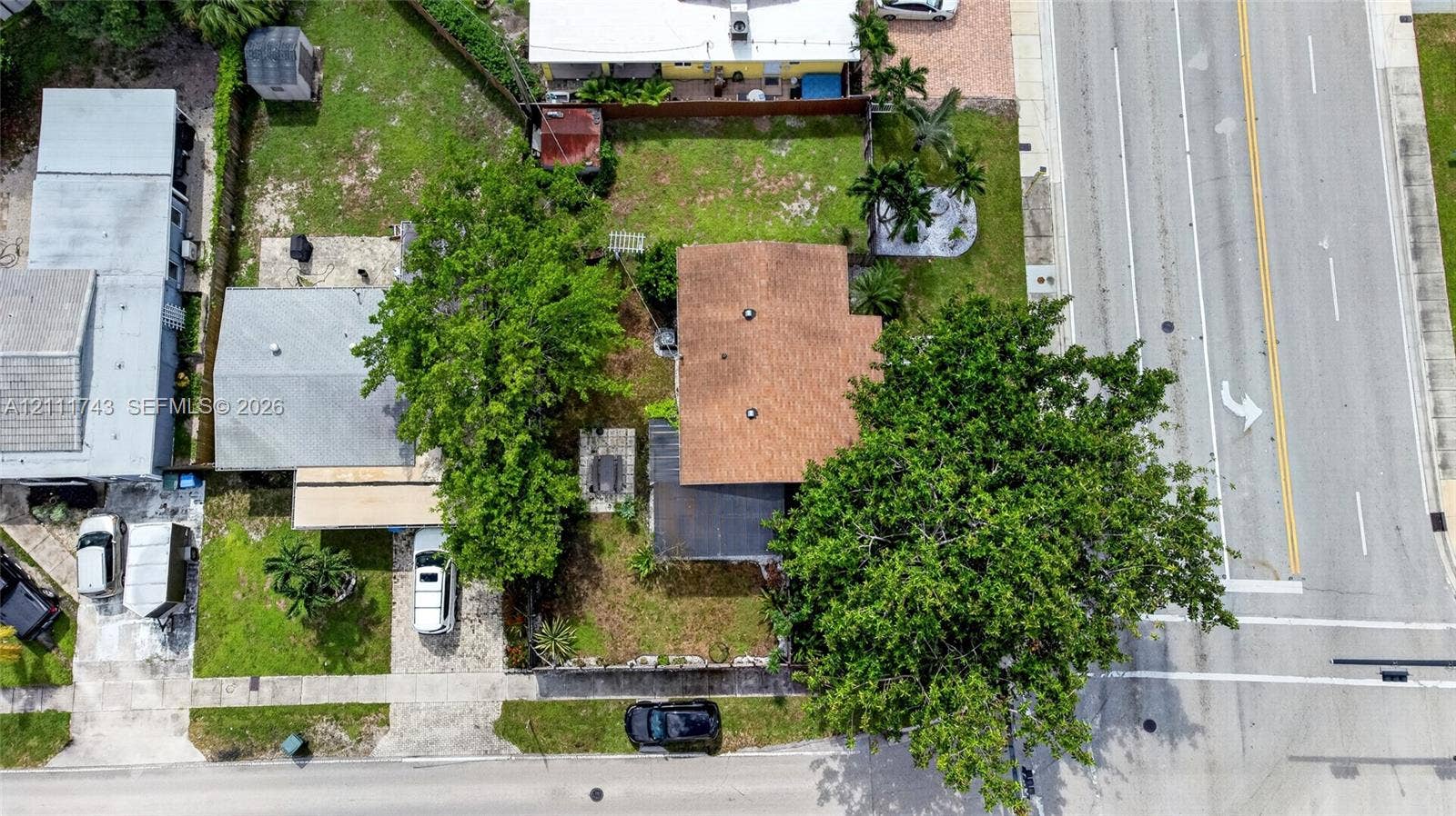5524 N Andrews Avenue, Oakland Park, FL 33309 Aerial perspective of the property featuring a structured lot, paved driveway, mature trees, and designated hardscaped area