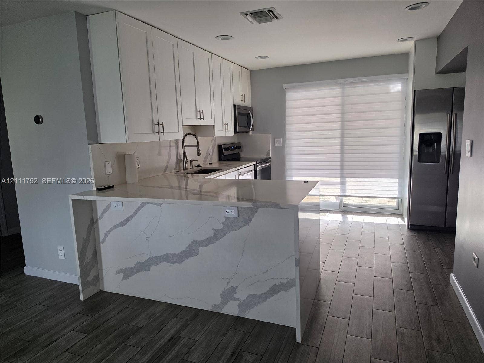 2901 NE 11th Terrace, Pompano Beach, Pompano Beach, FL 33064 Kitchen featuring white cabinetry, stone-patterned waterfall countertop, stainless steel appliances, and wood-finish flooring
