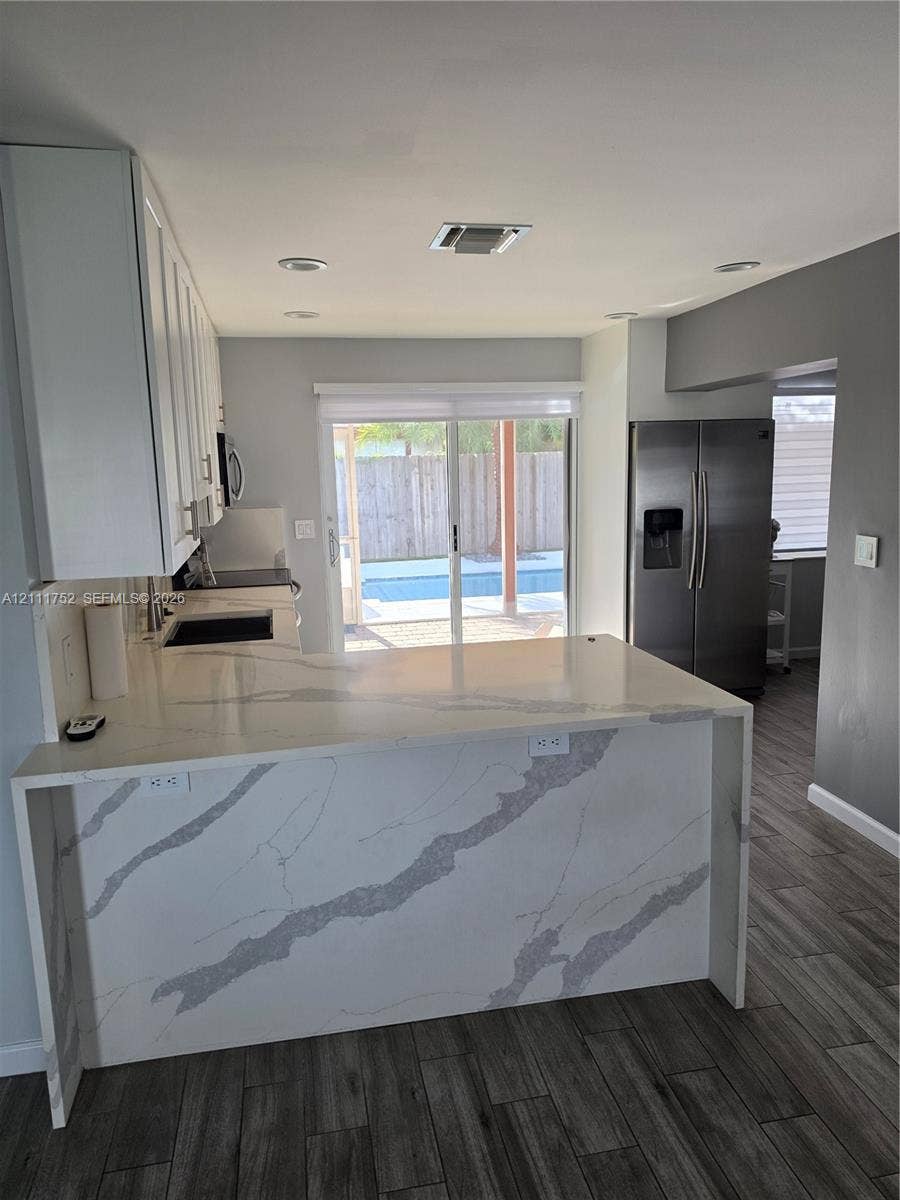 2901 NE 11th Terrace, Pompano Beach, Pompano Beach, FL 33064 Kitchen featuring a waterfall-edge stone countertop, white shaker-style cabinetry, stainless steel refrigerator, recessed lighting, and wood-finish flooring