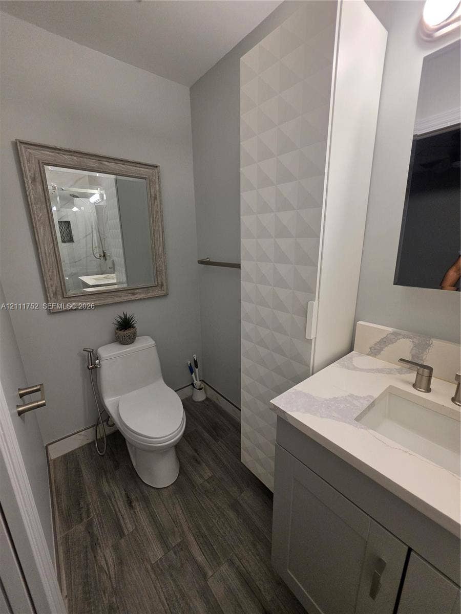 2901 NE 11th Terrace, Pompano Beach, Pompano Beach, FL 33064 Bathroom featuring a vanity with a white composite countertop, integrated rectangular sink, tall geometric-patterned storage cabinet, and wood-finish flooring