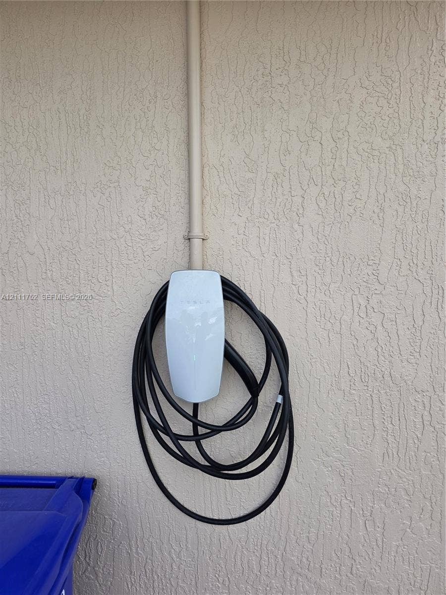 2901 NE 11th Terrace, Pompano Beach, Pompano Beach, FL 33064 Wall-mounted electric vehicle charging station with exterior conduit and textured stucco wall finish
