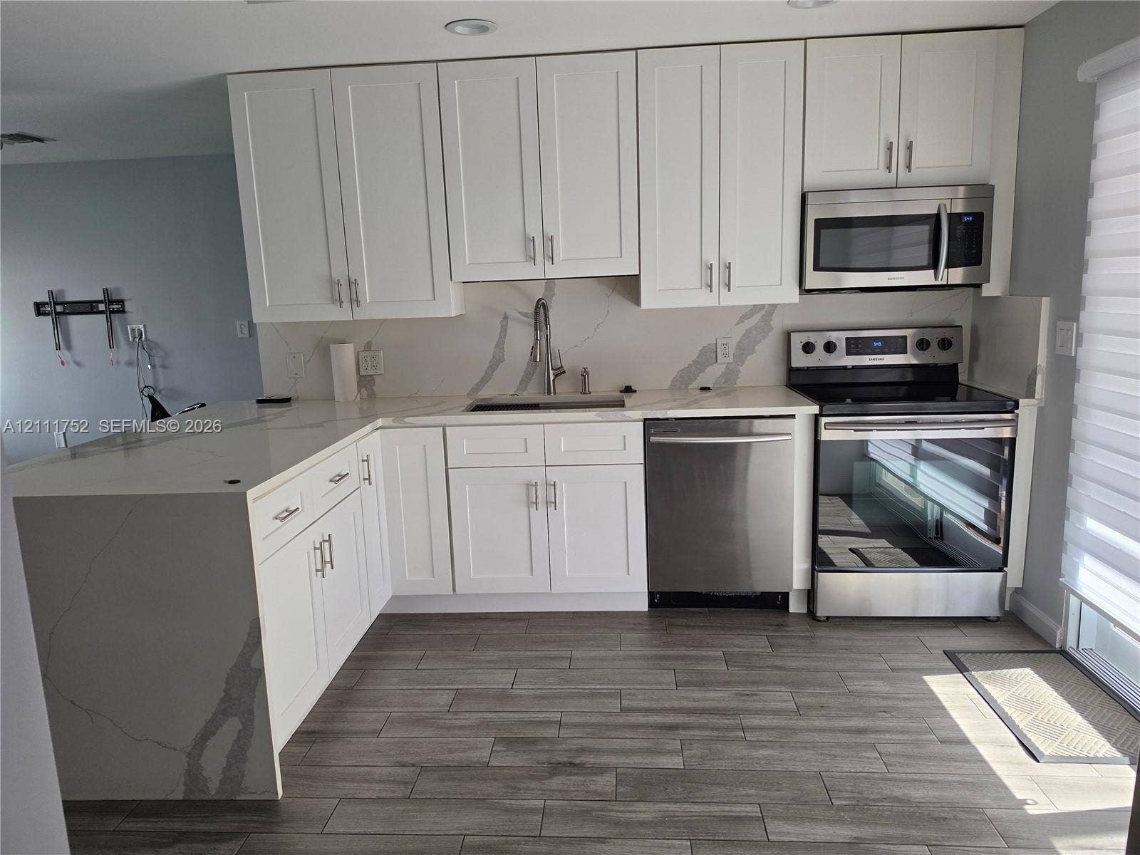 2901 NE 11th Terrace, Pompano Beach, Pompano Beach, FL 33064 Kitchen featuring white shaker-style cabinetry, quartz countertops with a waterfall edge, stainless steel appliances, and wood-finish tile flooring