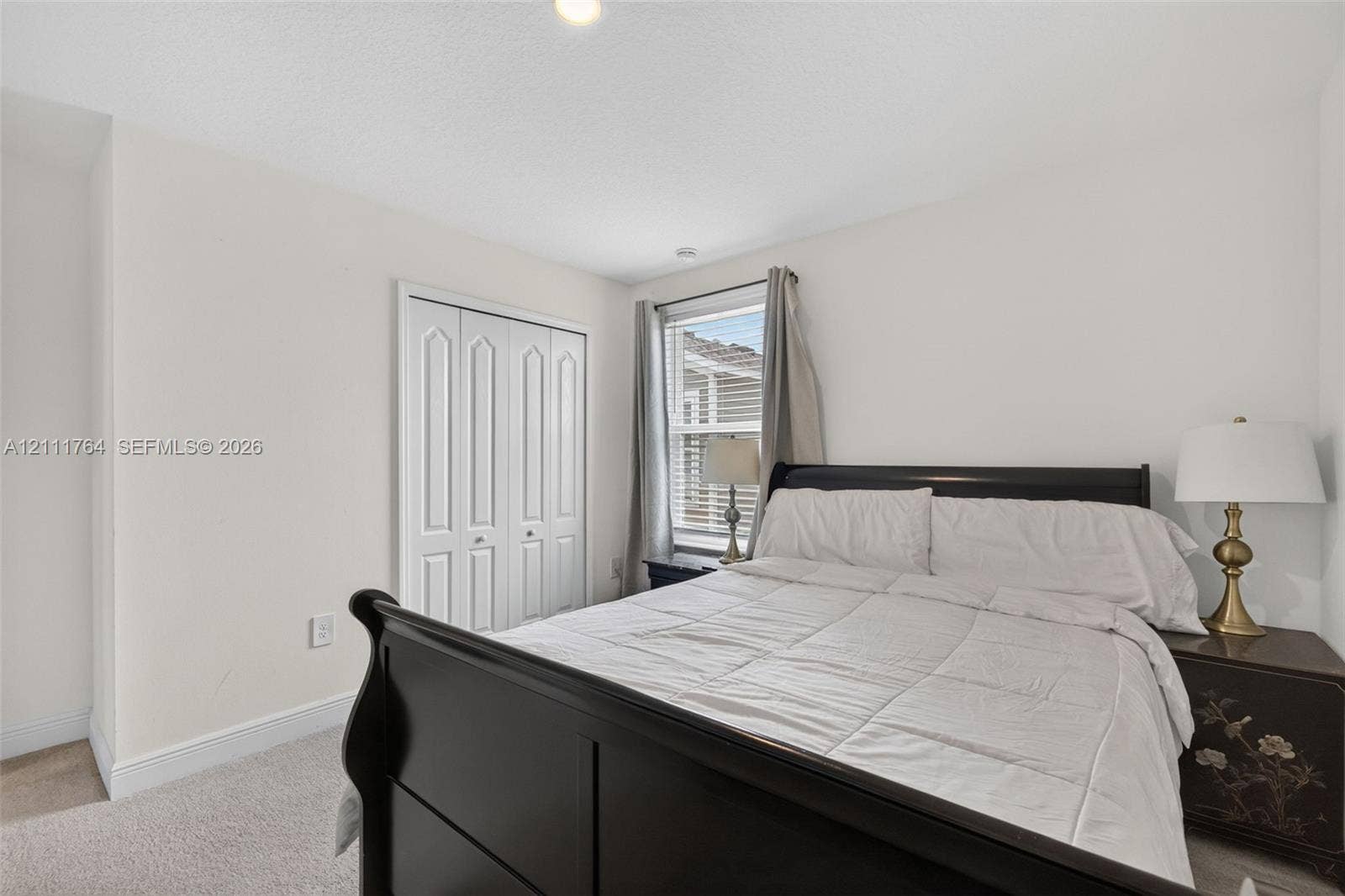 Neutral interior featuring carpeting, a single window, and white bi-fold closet doors