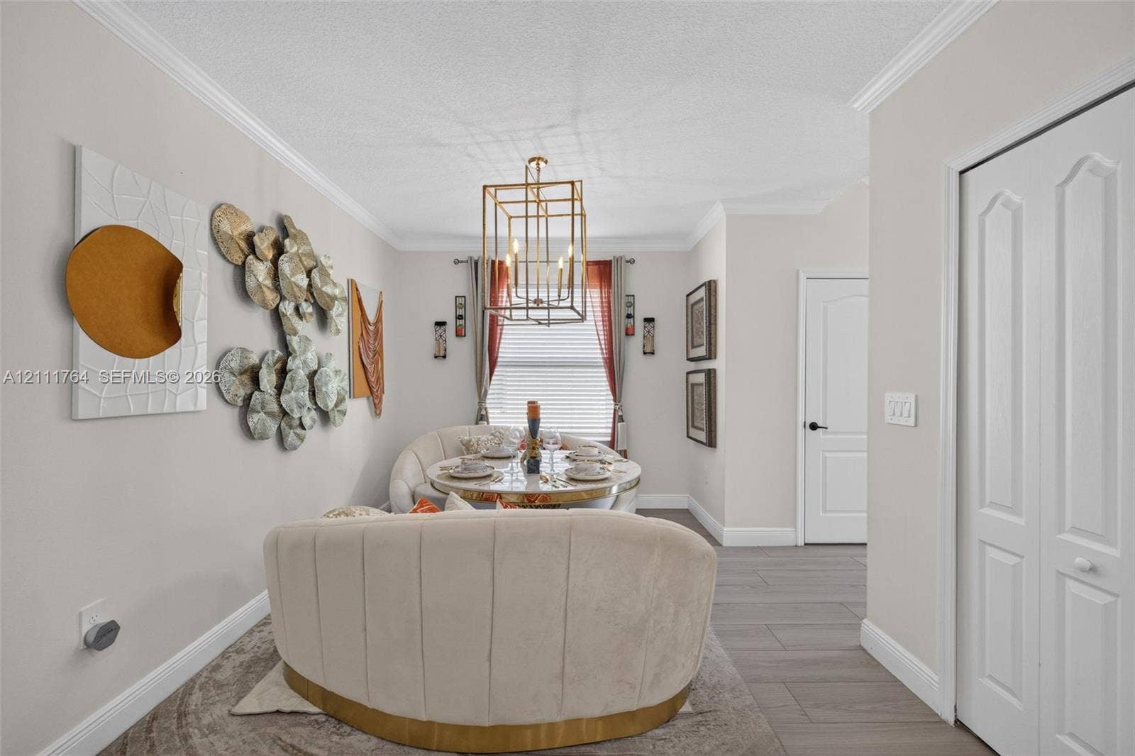 Neutral wall tones featuring a decorative geometric lantern-style pendant light, crown molding, wood-finish tile flooring, and arched-panel interior doors