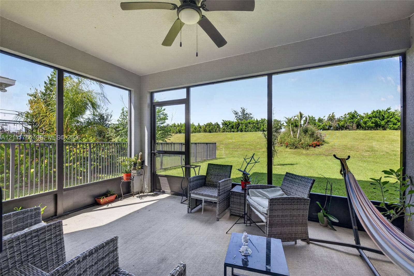 Screened-in lanai featuring a concrete floor, ceiling fan, and large panel screening