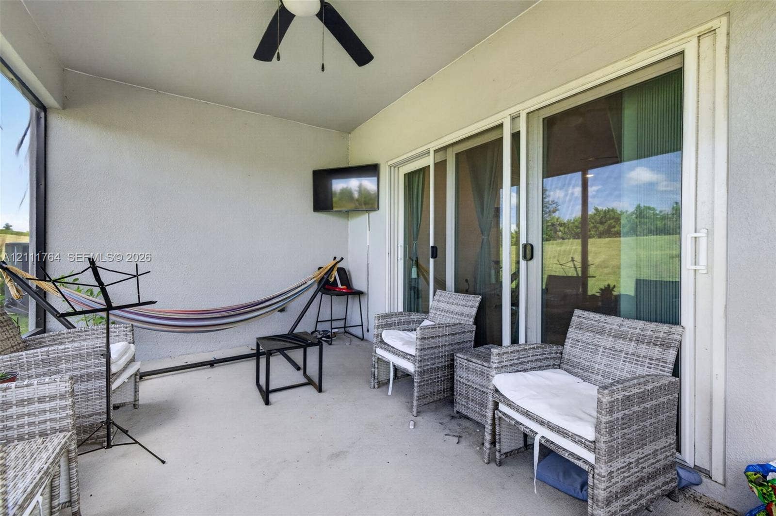 Screened lanai featuring concrete flooring, a ceiling fan, and sliding glass door access