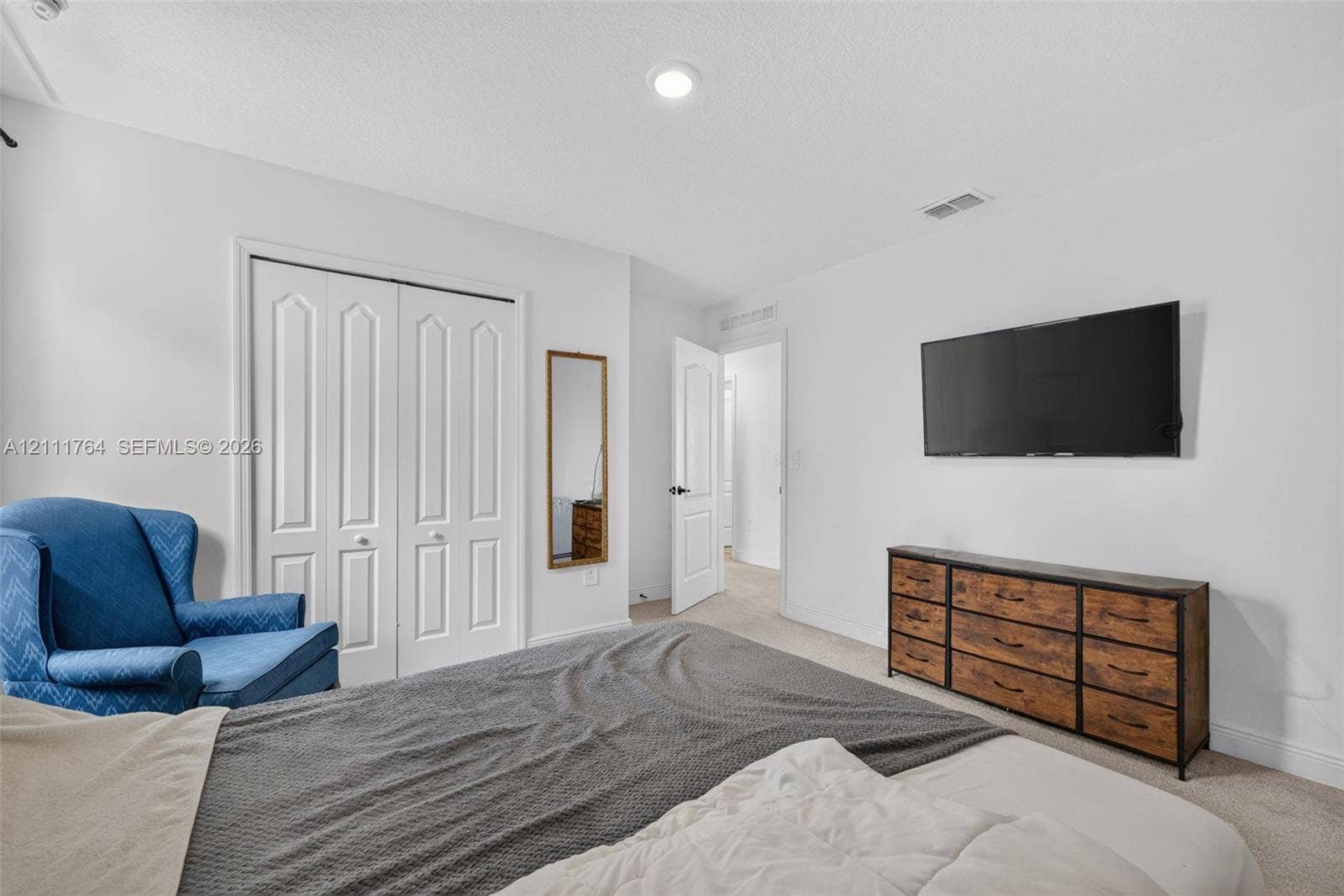 Room featuring neutral wall tones, recessed lighting, carpeted flooring, and a double-door closet with paneled detailing