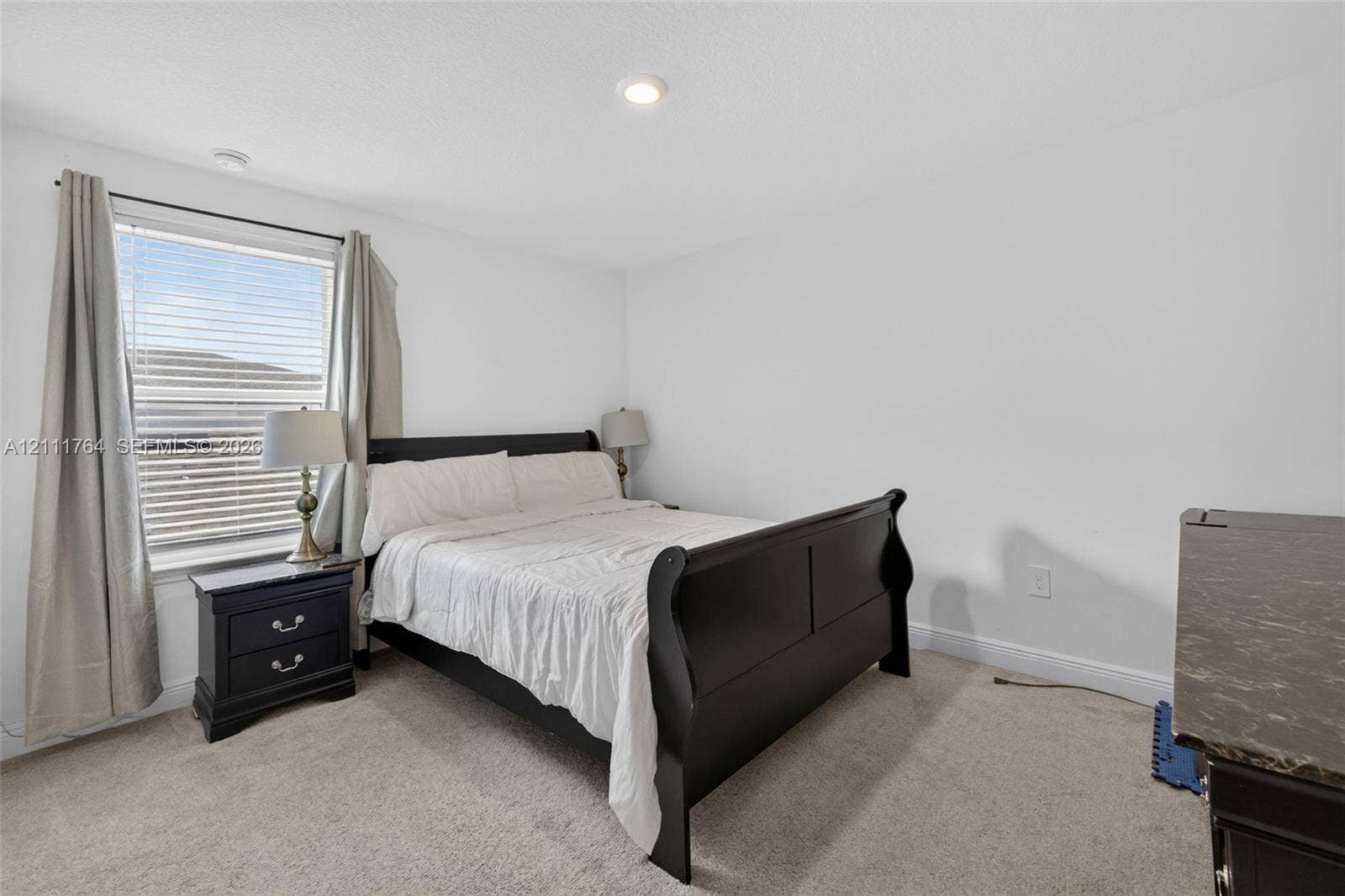 Bedroom featuring neutral wall-to-wall carpeting, recessed ceiling lighting, and a window with horizontal blinds