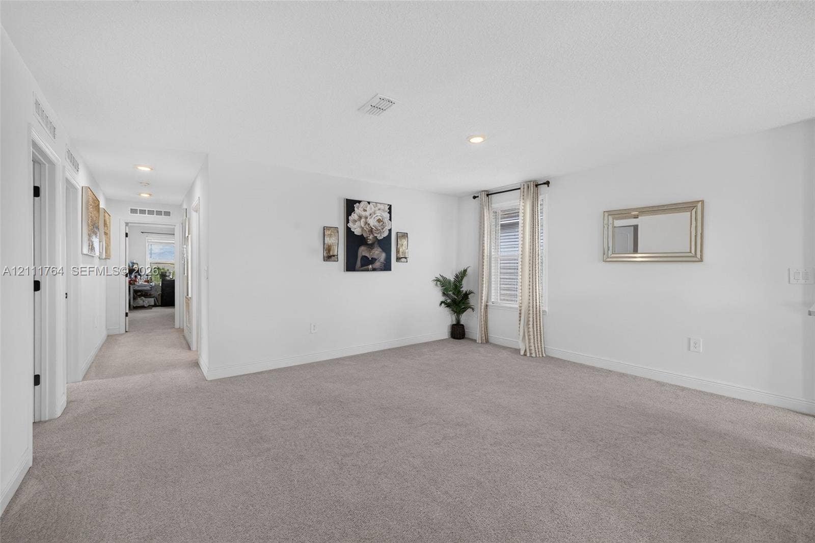 Interior space featuring neutral wall-to-wall carpeting, recessed ceiling lighting, and a window with exterior exposure