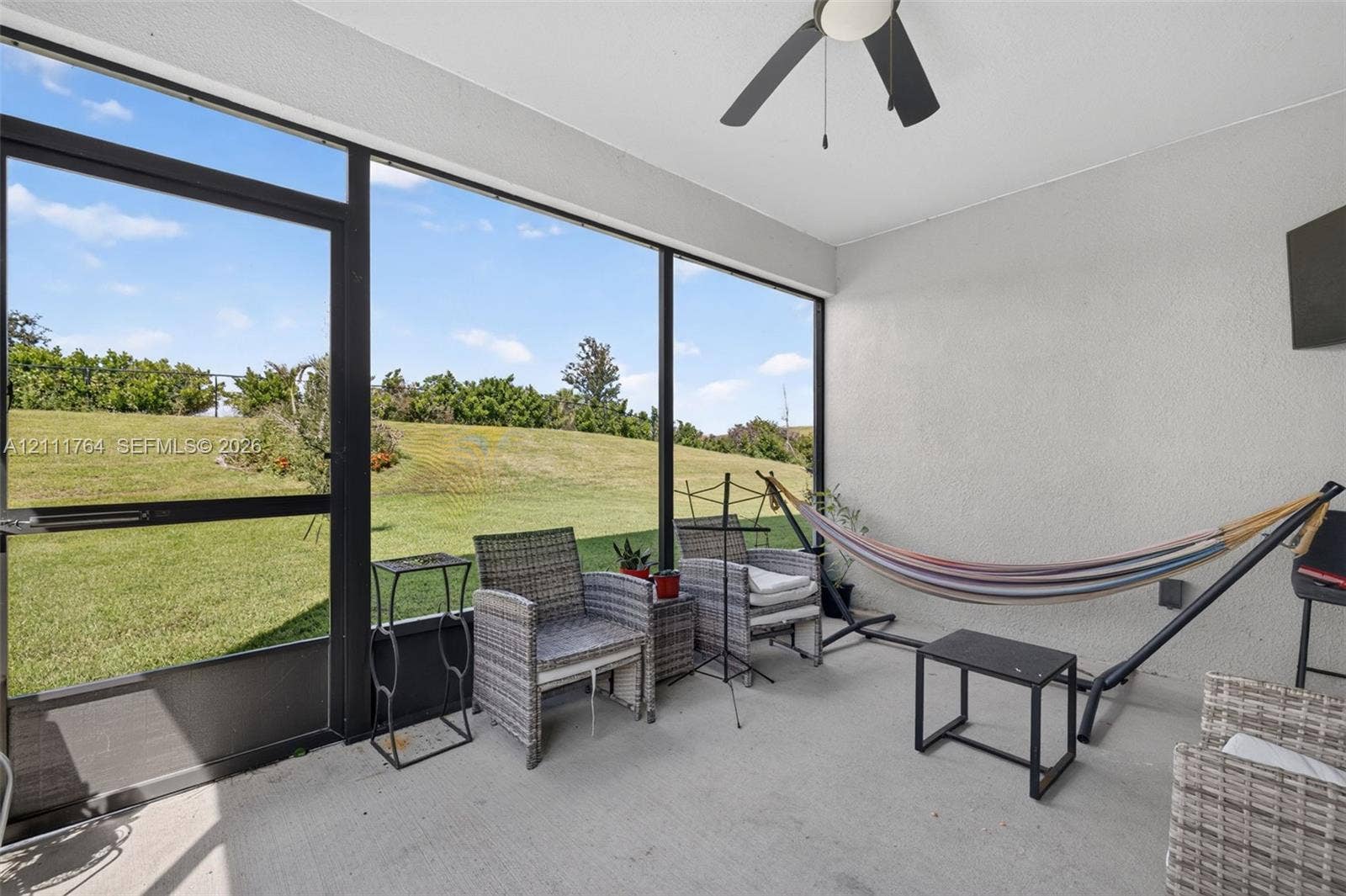 Screened lanai featuring floor-to-ceiling screens, concrete flooring, and a ceiling fan