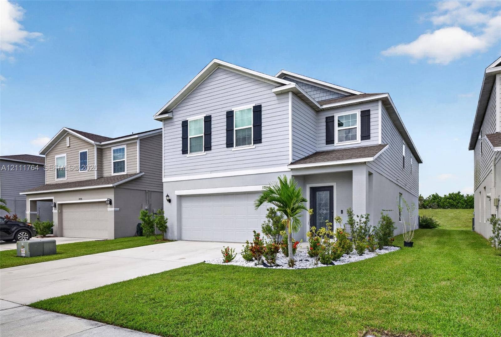 Two-story residence featuring horizontal lap and shake siding, a dual-tone exterior finish, a front-entry garage, and a landscaped rock garden bed