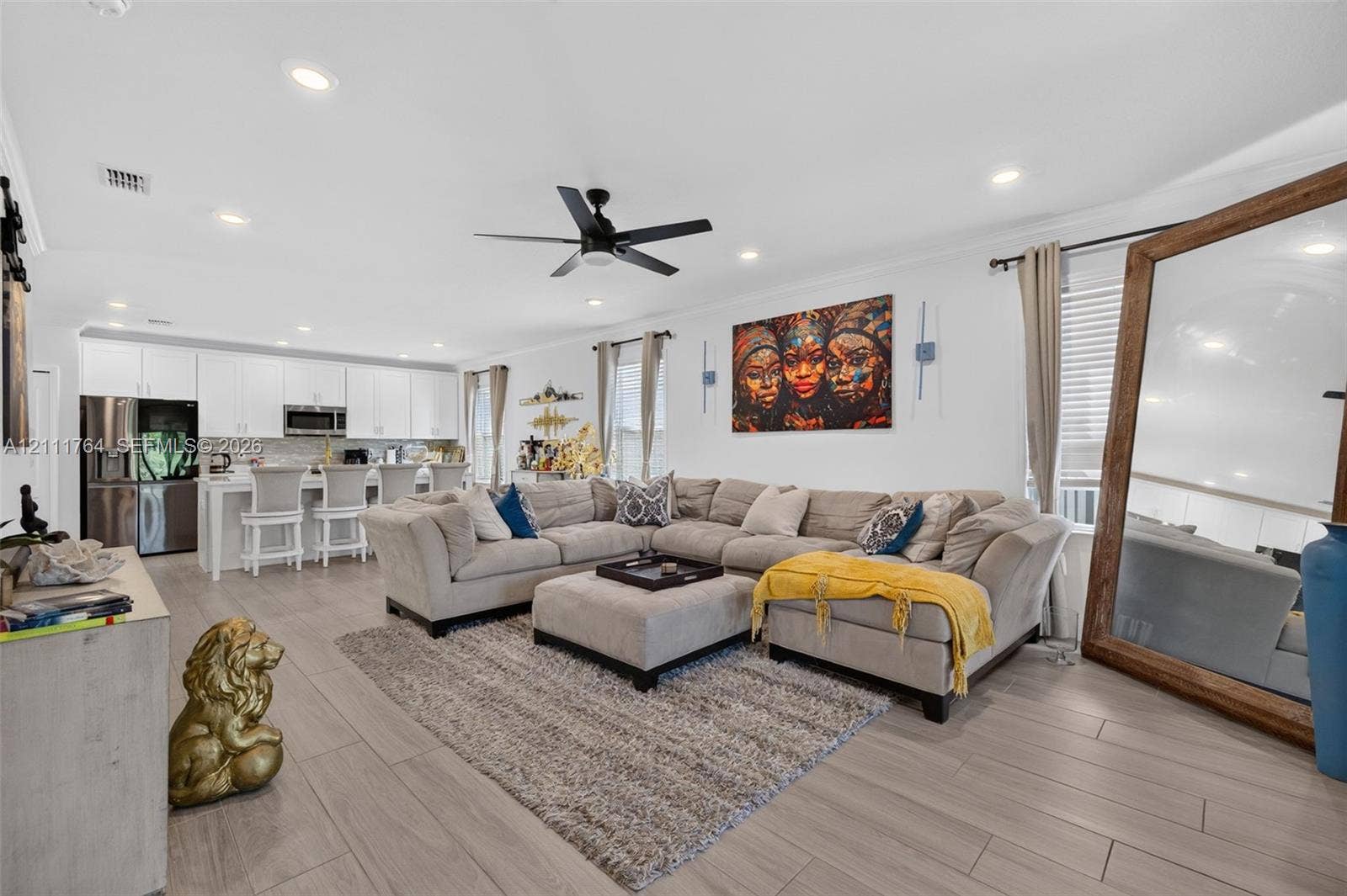 Open-concept interior featuring wood-finish flooring, recessed lighting, a modern ceiling fan, and white cabinetry with stainless steel appliances