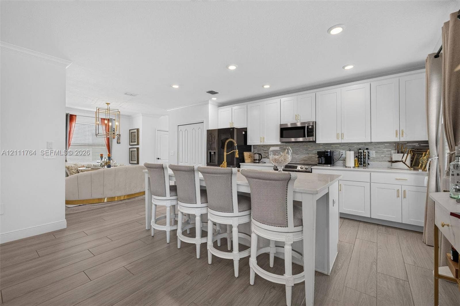Kitchen featuring white shaker-style cabinetry, a central island with a quartz countertop, recessed lighting, wood-finish flooring, and a stone tile backsplash