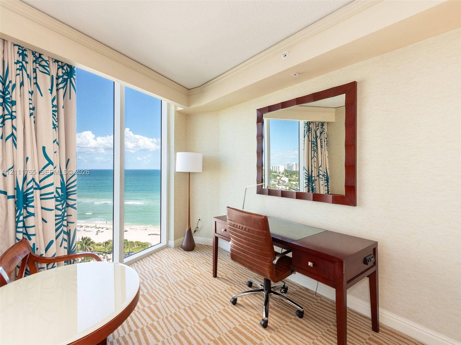 Floor-to-ceiling windows featuring ocean scenery, textured wall surfaces, and crown molding