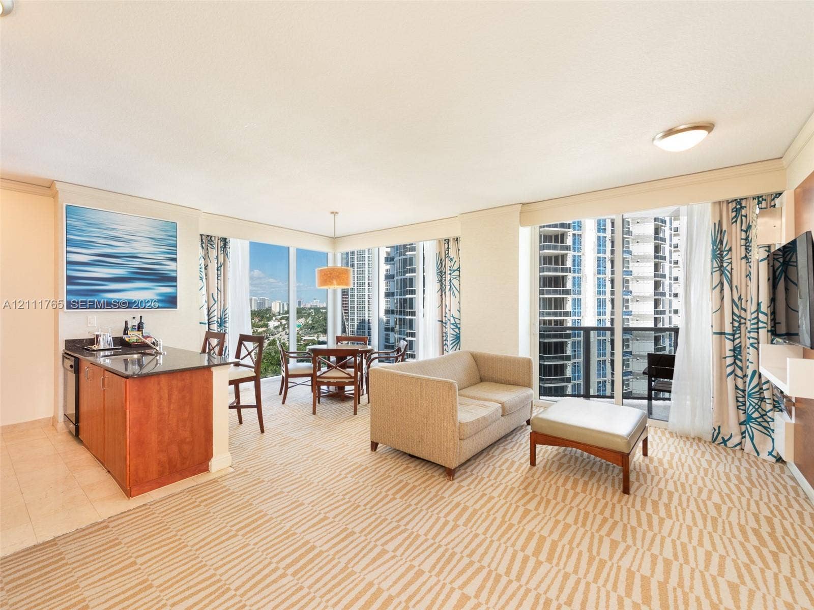 Floor-to-ceiling windows, built-in kitchenette with stone countertops, tiled flooring, and access to a private balcony