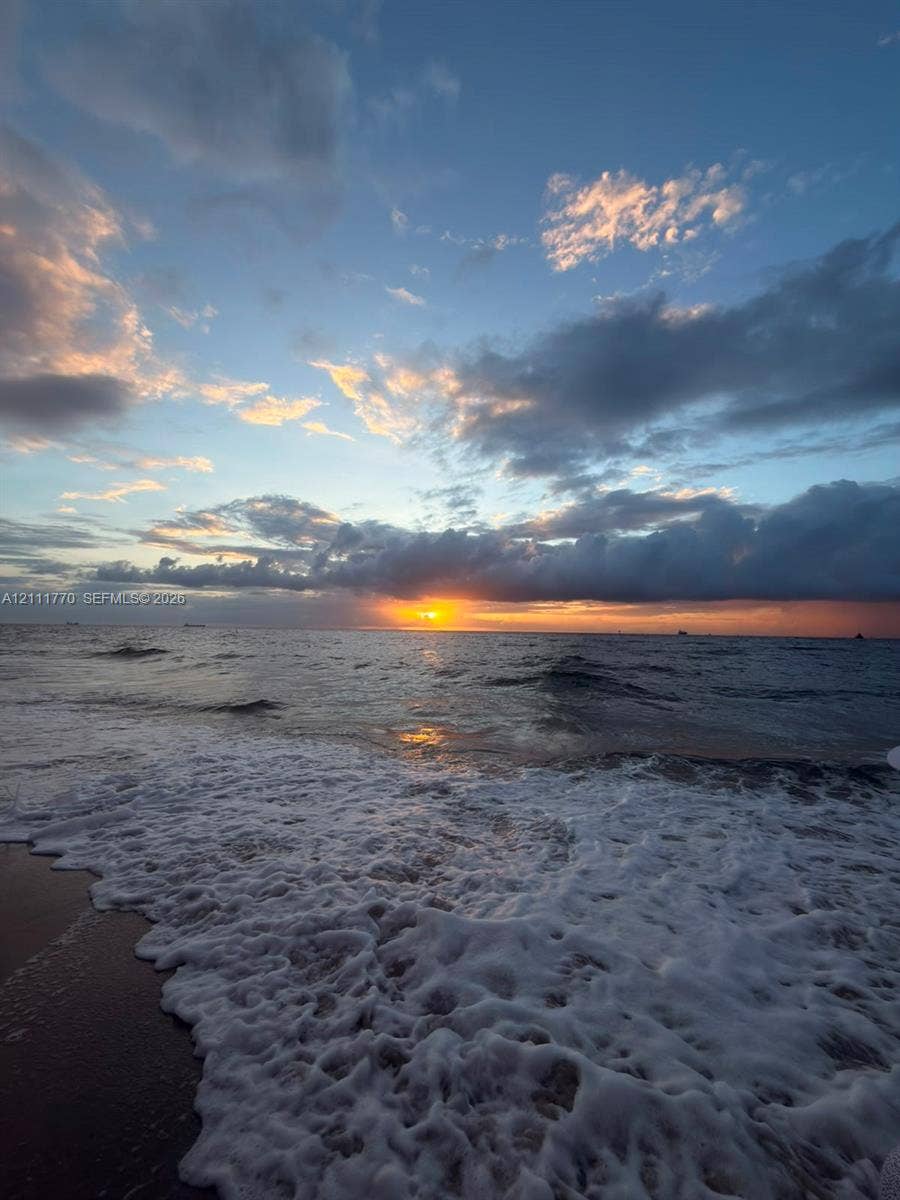 2200 S Ocean Lane, #2204, Fort Lauderdale, FL 33316 Oceanfront setting featuring direct water access, sandy beach terrain, and a horizon sunset