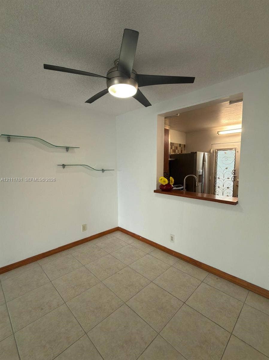 900 NE 12th Avenue, #401, Hallandale Beach, Hallandale Beach, FL 33009 Tile flooring, five-blade ceiling fan with integrated lighting, wall-mounted glass shelving, and wood-trim service window