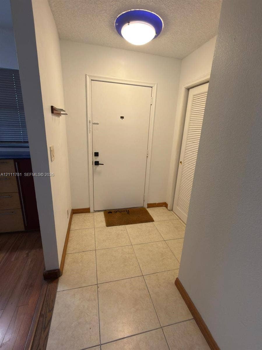 900 NE 12th Avenue, #401, Hallandale Beach, Hallandale Beach, FL 33009 Entryway featuring large-format neutral floor tile, a solid door with matte black hardware, and a louvered closet door