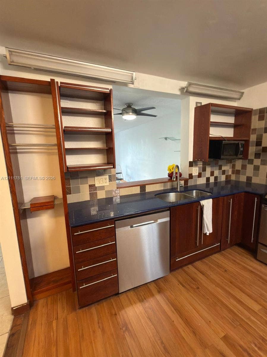 900 NE 12th Avenue, #401, Hallandale Beach, Hallandale Beach, FL 33009 Kitchen featuring wood cabinetry with built-in open shelving, dark countertops, a double-basin stainless steel sink, stainless steel dishwasher, and multi-toned tile backsplash