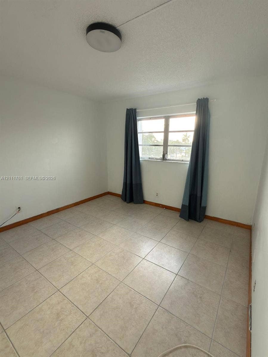 900 NE 12th Avenue, #401, Hallandale Beach, Hallandale Beach, FL 33009 Room featuring neutral ceramic tile flooring, a horizontal multi-pane window, and a circular flush-mount ceiling light