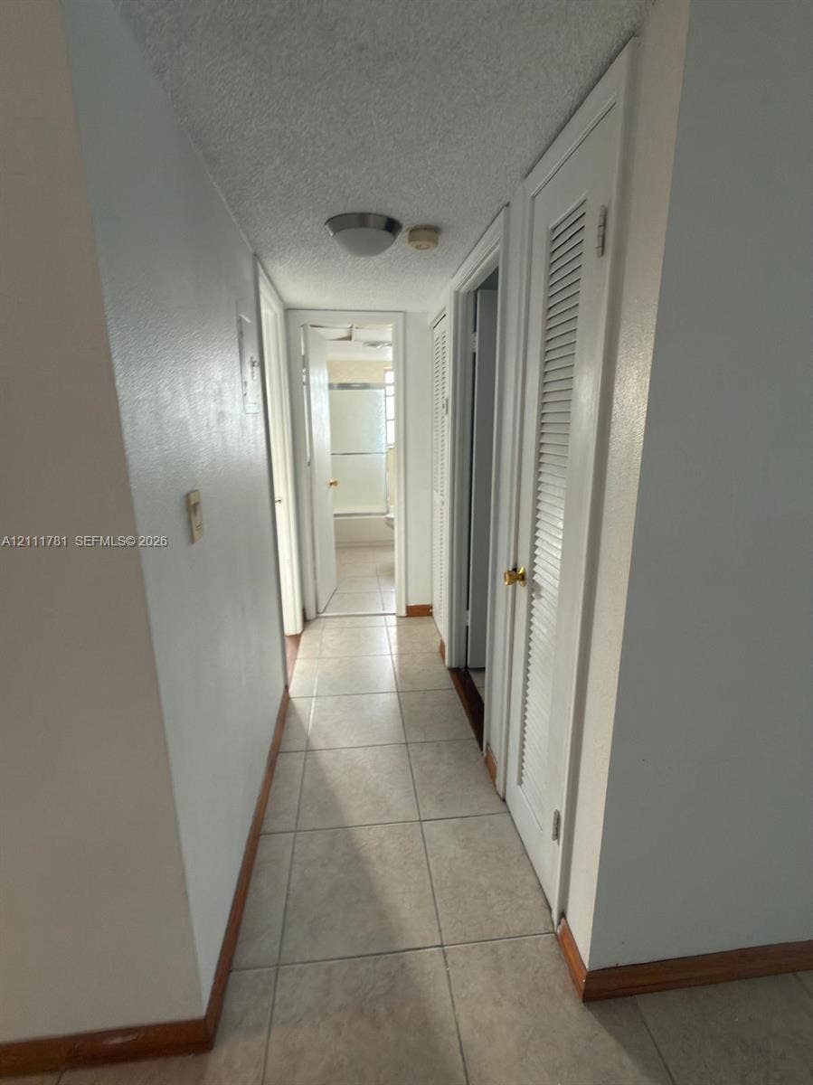 900 NE 12th Avenue, #401, Hallandale Beach, Hallandale Beach, FL 33009 Hallway featuring ceramic tile flooring, neutral wall paint, and closet doors with louvered panels