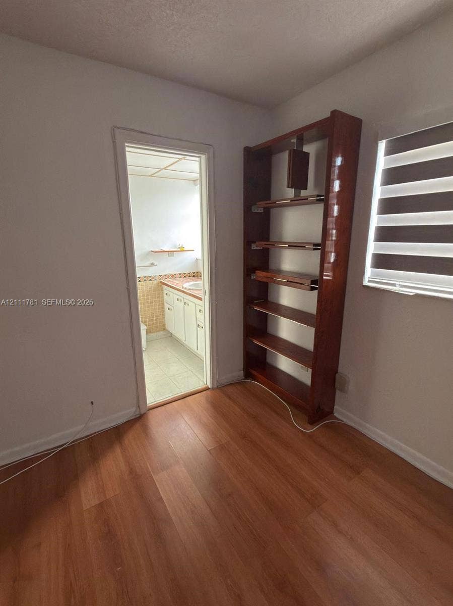 900 NE 12th Avenue, #401, Hallandale Beach, Hallandale Beach, FL 33009 Wood-finish flooring, built-in wooden shelving unit, and a window with a dual-layer roller shade