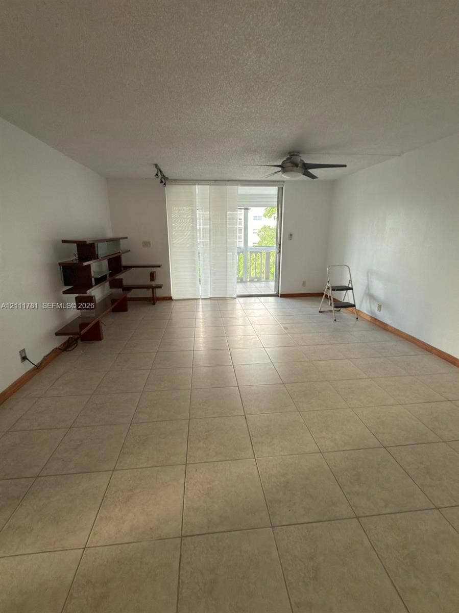 900 NE 12th Avenue, #401, Hallandale Beach, Hallandale Beach, FL 33009 Neutral-toned ceramic tile flooring, ceiling-mounted fan, and glass sliding doors leading to an exterior balcony