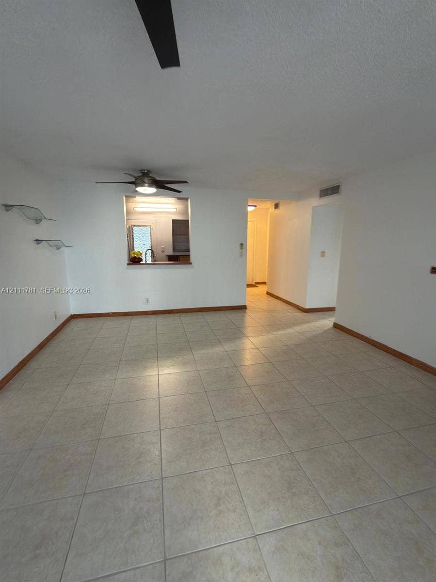 900 NE 12th Avenue, #401, Hallandale Beach, Hallandale Beach, FL 33009 Interior space featuring neutral tile flooring, ceiling-mounted fan, and wall-mounted glass display shelving