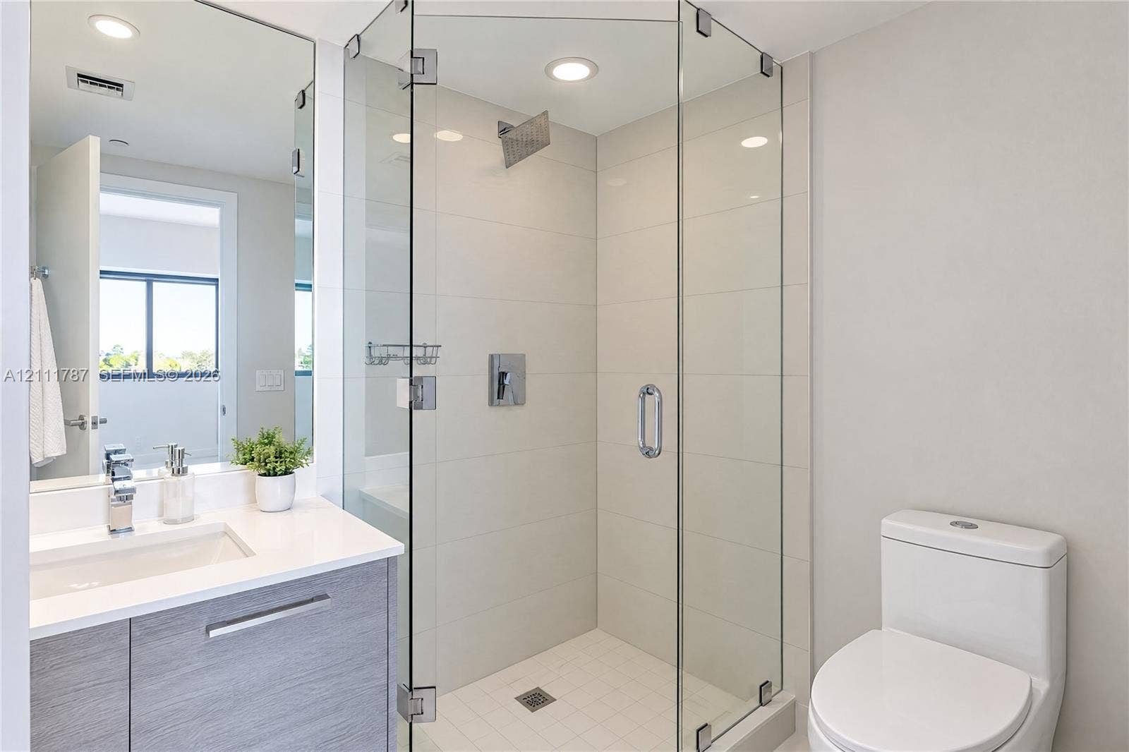 Bathroom featuring a glass-enclosed shower with tiled surround, floating vanity with a stone-finish countertop, undermount sink, and polished chrome hardware