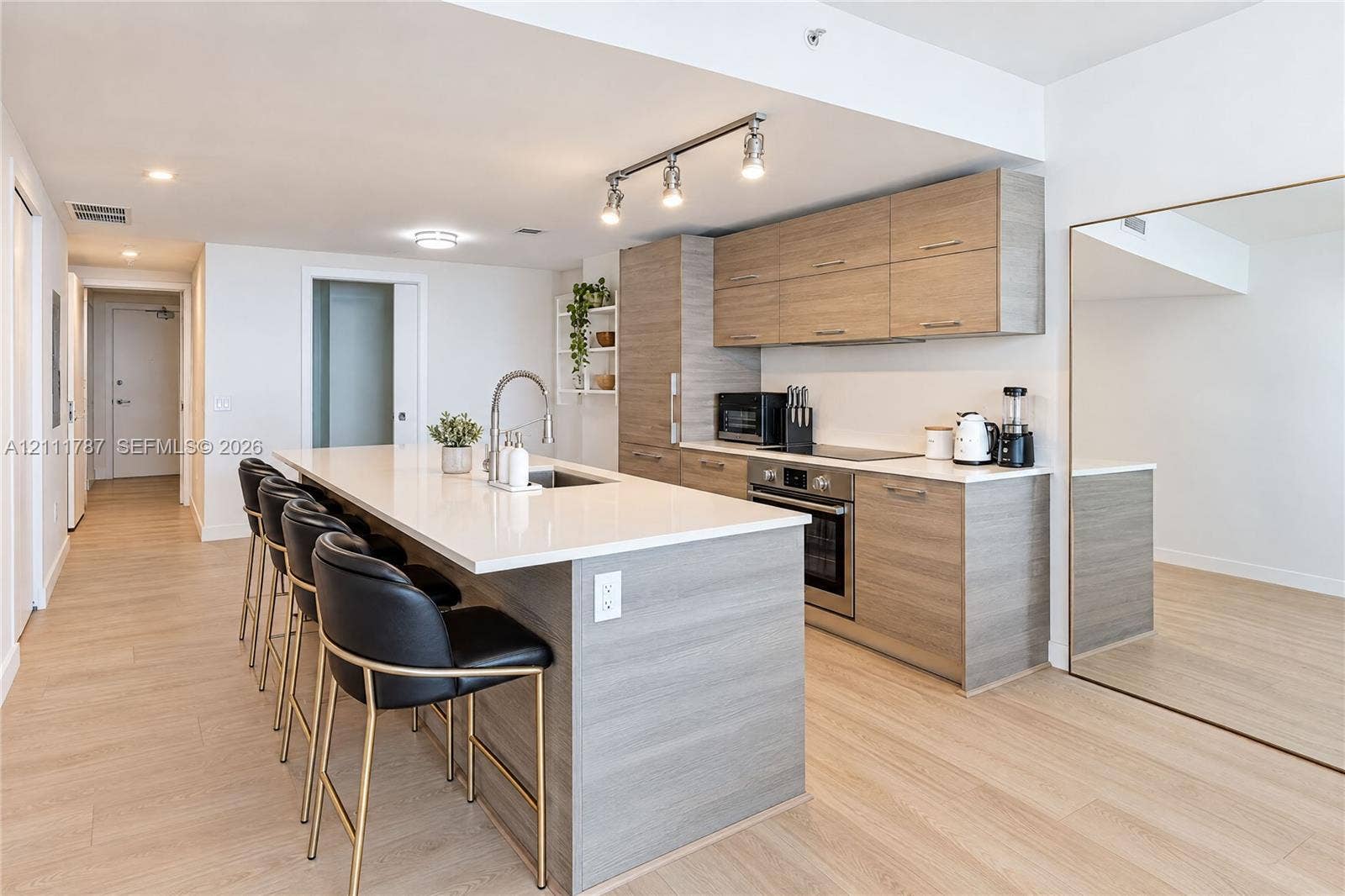 Kitchen featuring wood-finish cabinetry, quartz countertops, a kitchen island, stainless steel appliances, and wood-finish flooring