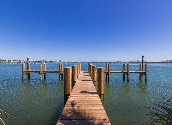 Private wood-plank dock featuring structural pilings and a T-shaped configuration extending over the water