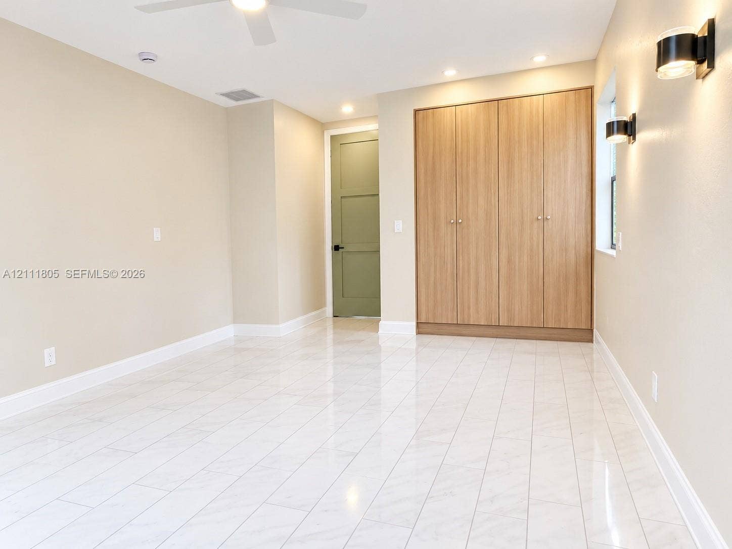 Polished tile flooring, floor-to-ceiling built-in cabinetry with wood-finish doors, matte black wall-mounted fixtures, and a green three-panel interior door
