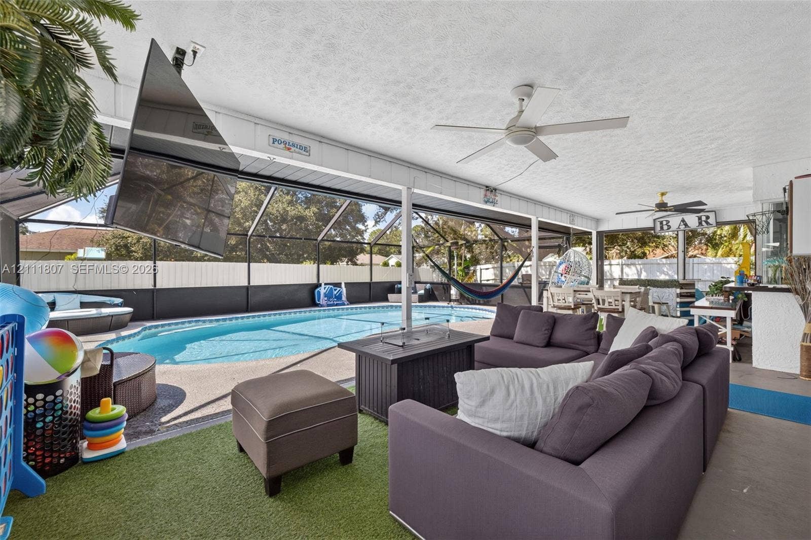 Covered outdoor patio featuring a screened enclosure, in-ground swimming pool, ceiling fans, and a built-in bar
