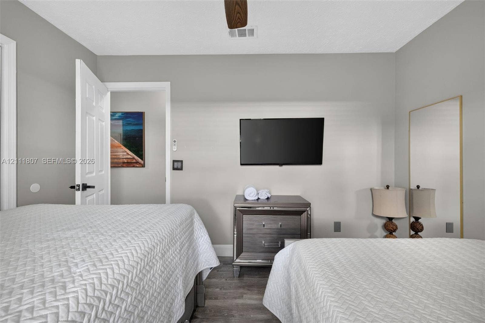 Room featuring neutral walls, wood-finish flooring, and a ceiling fan with integrated lighting
