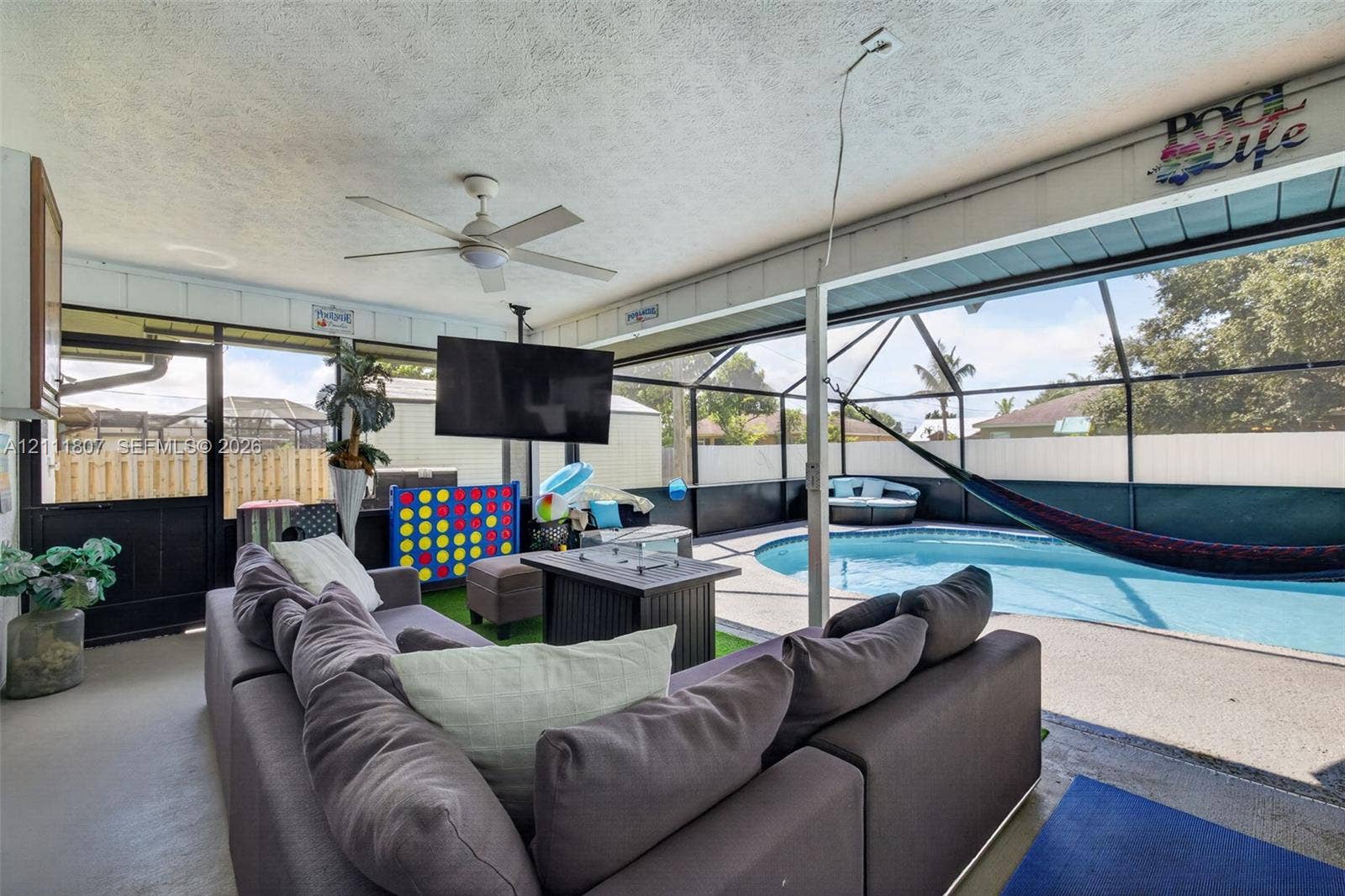 Screened-in lanai featuring a concrete patio, built-in ceiling fan, and in-ground swimming pool